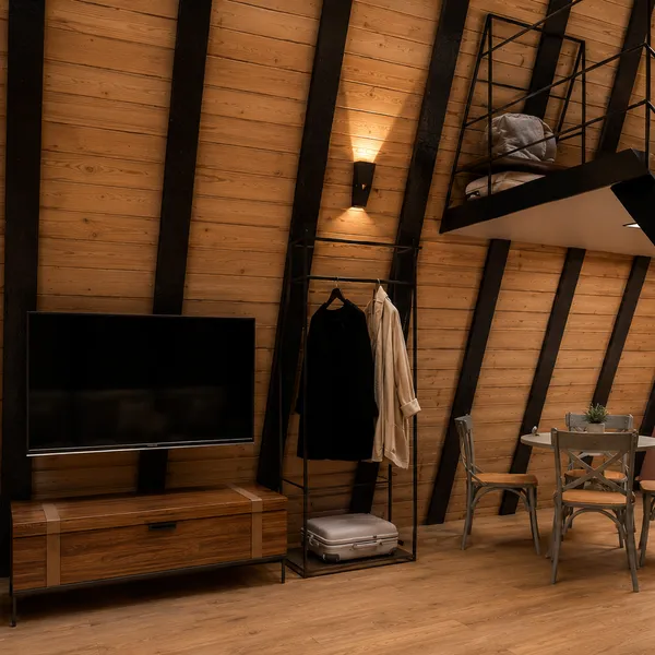 Sala do chalé com TV, arara de roupas e escada para o loft