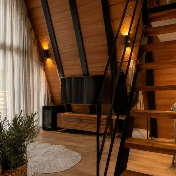 Interior do chalé com cortinas, escada de madeira e luz natural